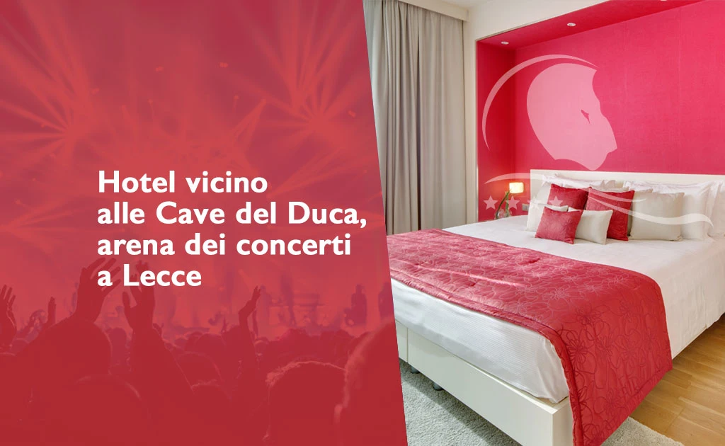 Immagine promozionale con camera dell'hotel con pareti bianche e una parete rossa decorata. Il letto matrimoniale è rivestito con biancheria bianca e copriletto rosso, accompagnato da cuscini rossi e bianchi. In sovraimpressione il logo dell'hotel. Sul lato sinistro dell’immagine, su sfondo rosso con silhouette di pubblico e luci da concerto, è presente il testo: “Hotel vicino alle Cave del Duca, arena dei concerti a Lecce”. L’ambiente è luminoso, con tende chiare e pavimento in legno chiaro.